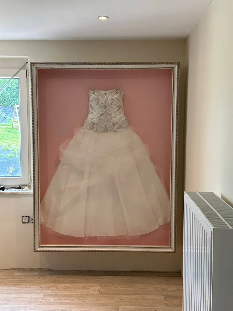 een witte bruidsjurk gepresenteerd in een luxe, verdiepte 3D-lijst door Atelier Vanduca
