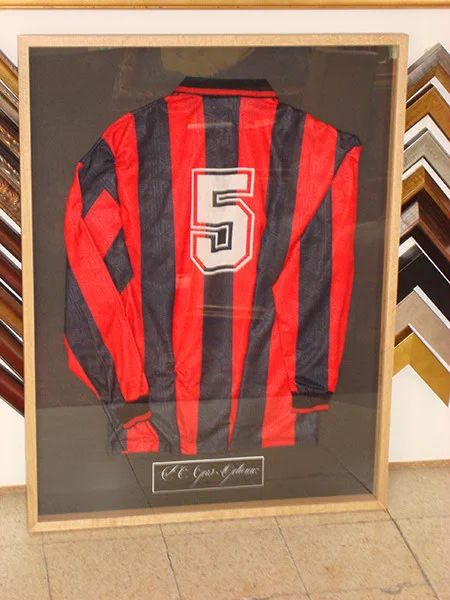 Klassiek rood-zwart voetbalshirt conserverend ingelijst in een houten kader